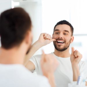 young man flossing in mirror