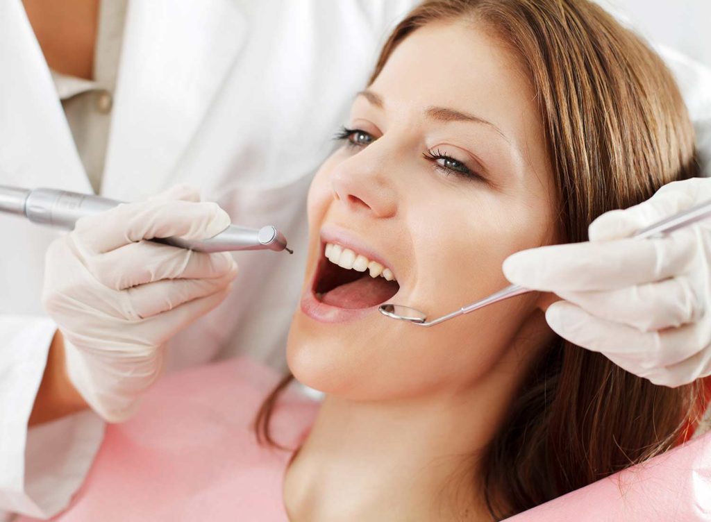 happy young woman getting teeth cleaned
